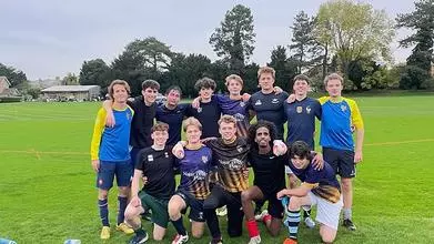 The Trinity College Football team crouched together on the pitch