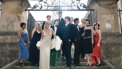Actors from the Trinity players posing in front of a gate