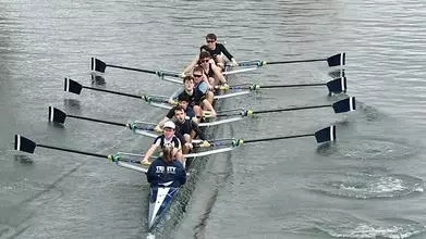 A boat of Trinity members rowing down the river