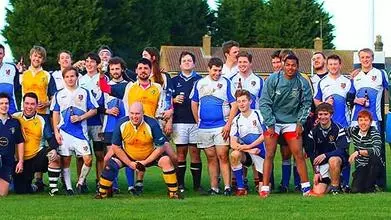 The Trinity college Rugby team crouched together on the pitch