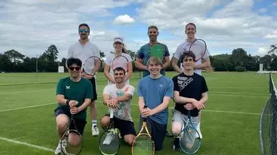 Members of the Trinity Tennis society crouched on a grass court