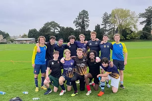 The Trinity College Football team crouched together on the pitch