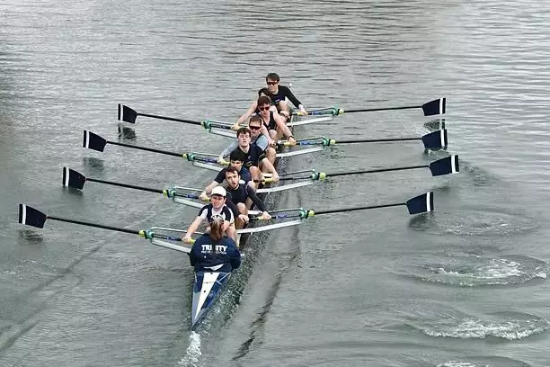 A boat of Trinity members rowing down the river
