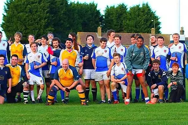 The Trinity college Rugby team crouched together on the pitch