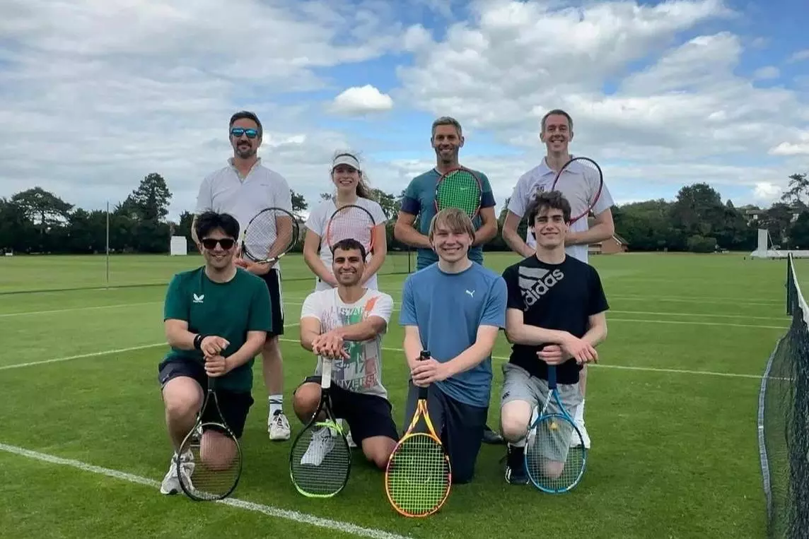 Members of the Trinity Tennis society crouched on a grass court